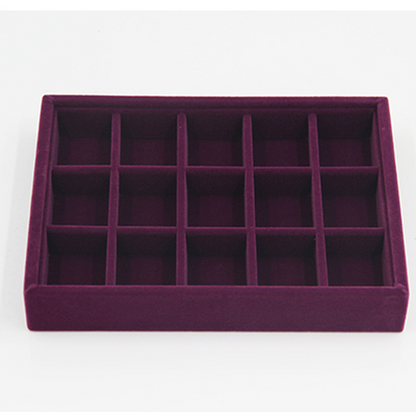 Gray velvet jewelry tray with grid compartments for stackable, elegant storage of watch accessories.