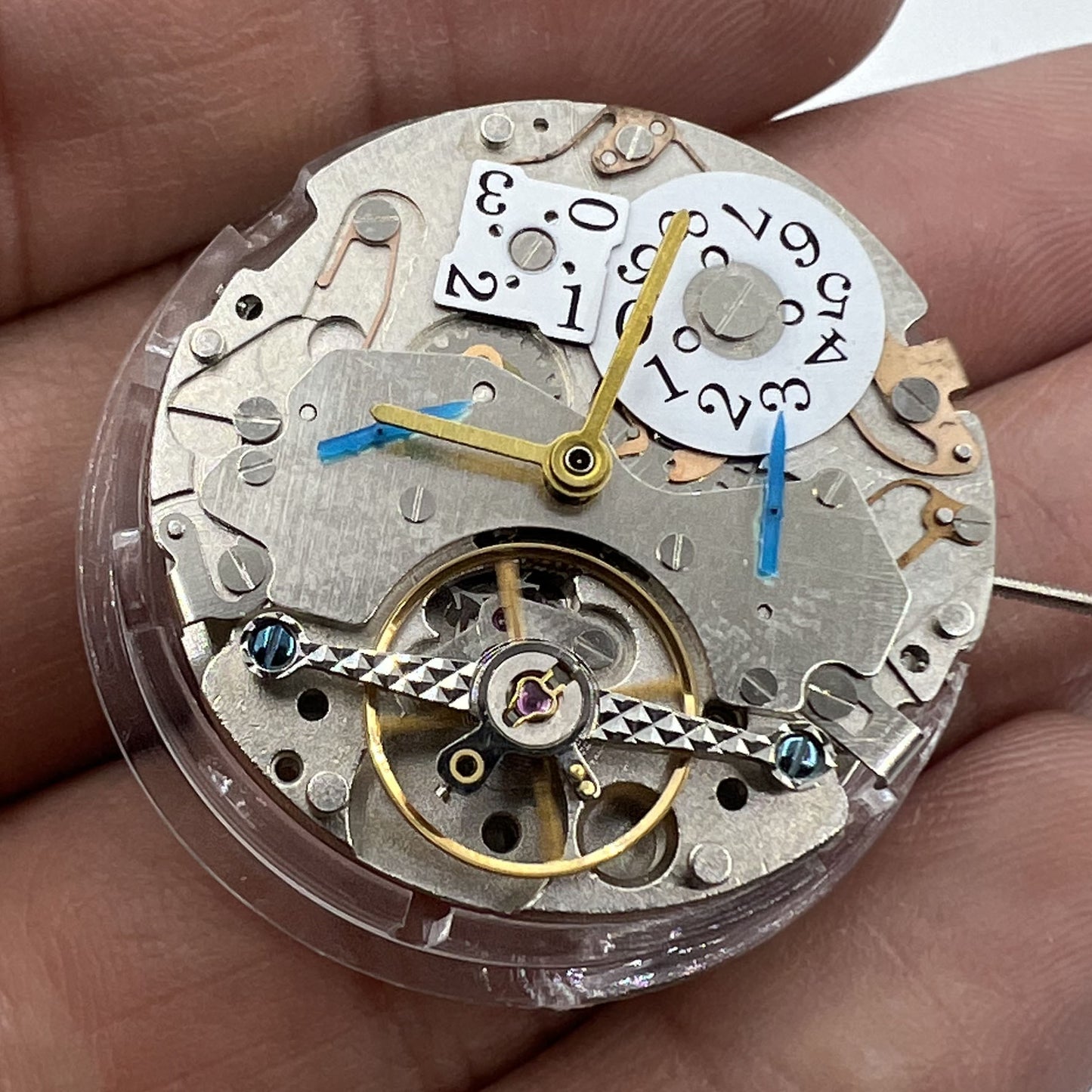 Asian brand multifunctional watch showcasing automatic mechanical movement with date at 12 and visible bare balance wheel.