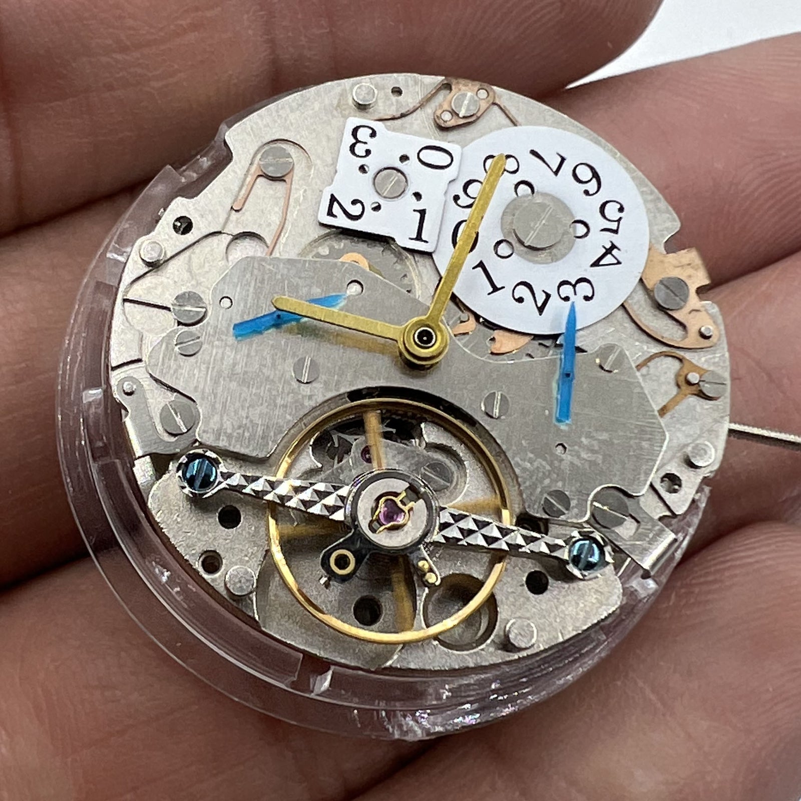 Asian brand multifunctional watch showcasing automatic mechanical movement with date at 12 and visible bare balance wheel.