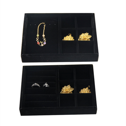 Gray velvet jewelry tray featuring grid compartments for stackable accessory storage.