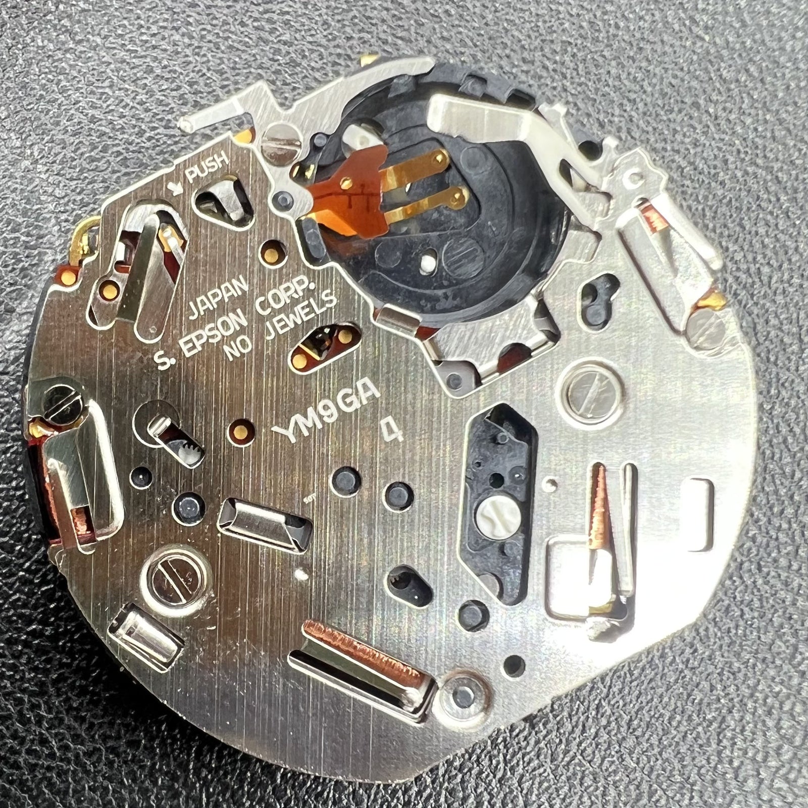 Hattori Epson YM9G quartz watch movement, precise timekeeping mechanism for watch repairs.
