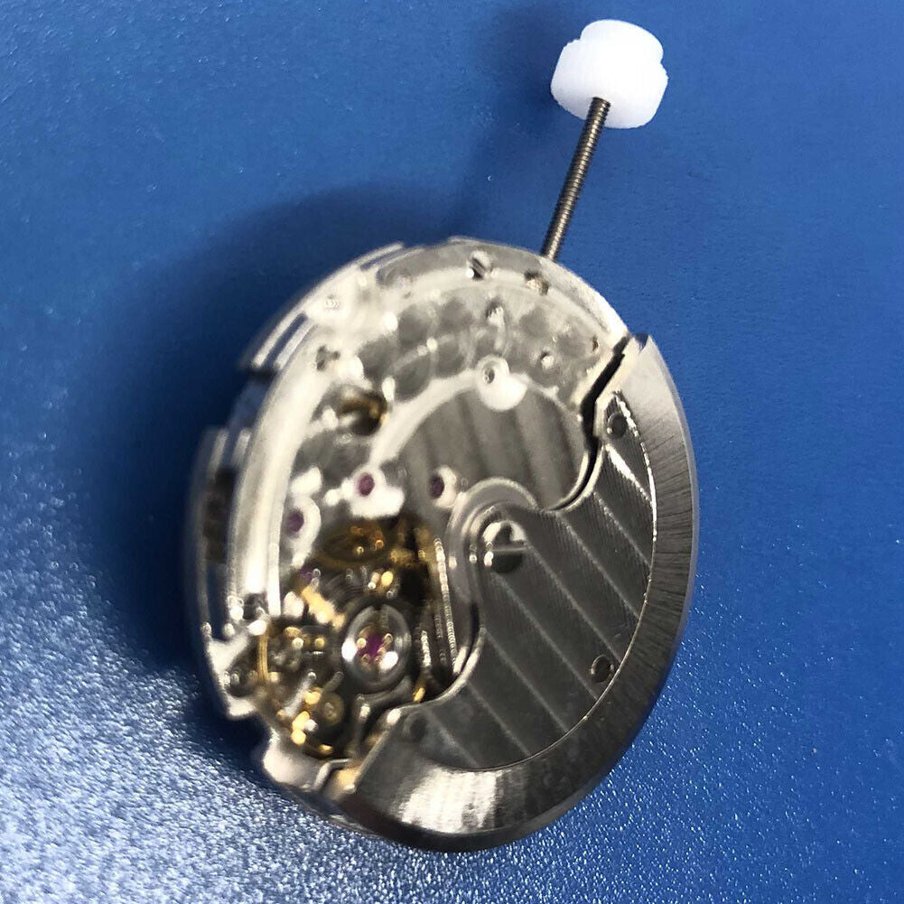Close-up of DG2813 automatic mechanical watch movement with silver gears and date display at 3 o'clock.