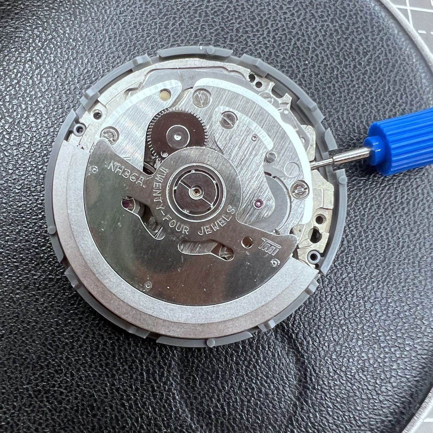 Seiko NH36A automatic watch movement with black finish and green luminescent markers, crown at 3:80 position.
