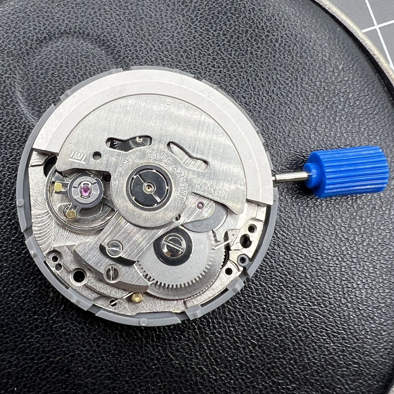 Black NH36A automatic watch movement showing precision mechanical gears with Roman wheel crown positioned at 3 o'clock by NH36.