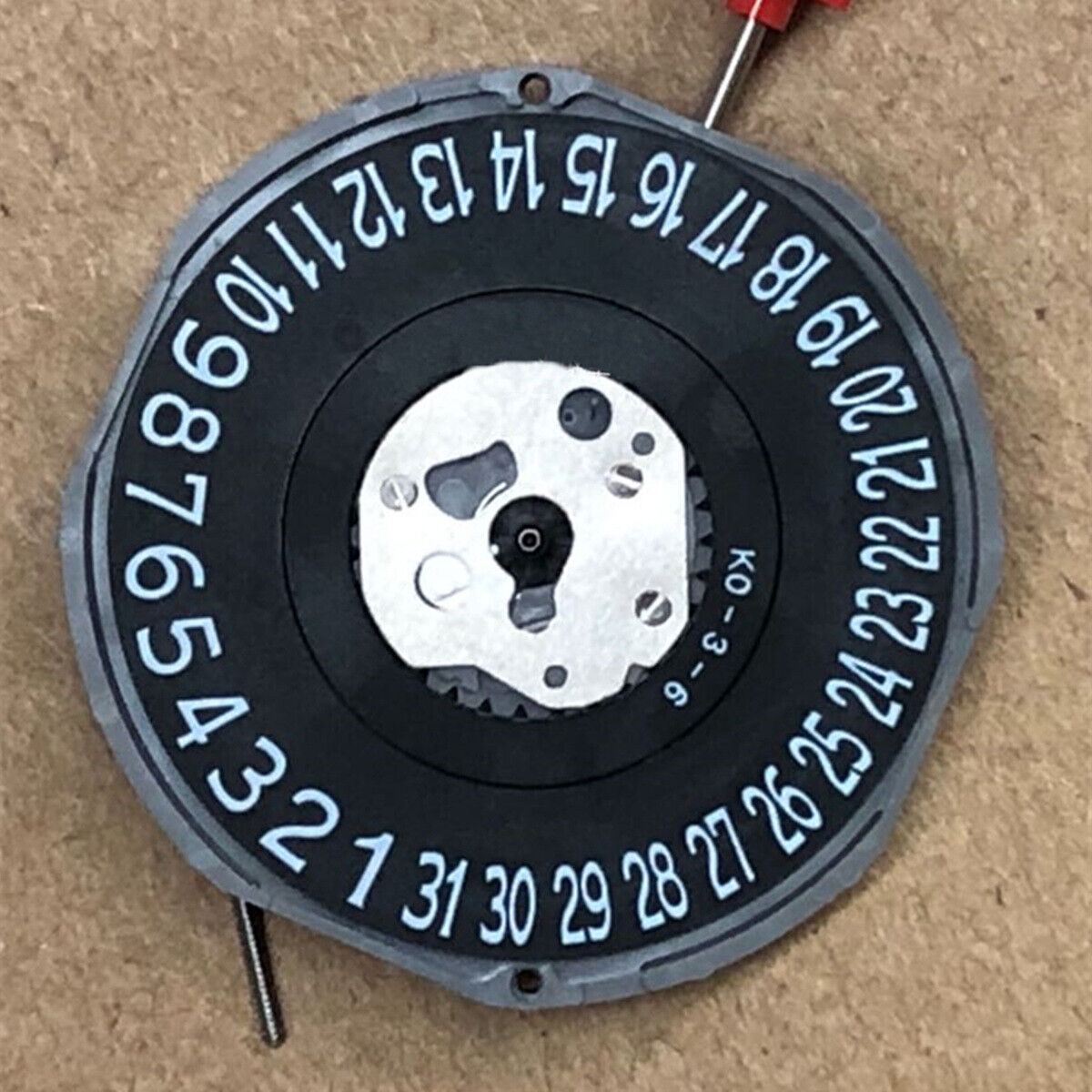 Quartz watch movement Miyota 2415 with 3 hands, black disk wheel, and date display at 6 o'clock.