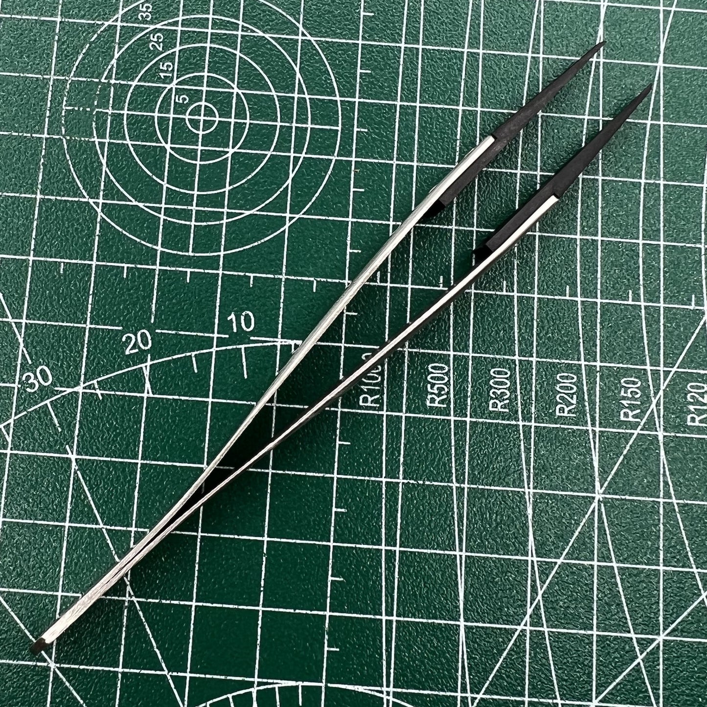 Precision stainless steel tweezers with carbon fiber tips for detailed watch repair.