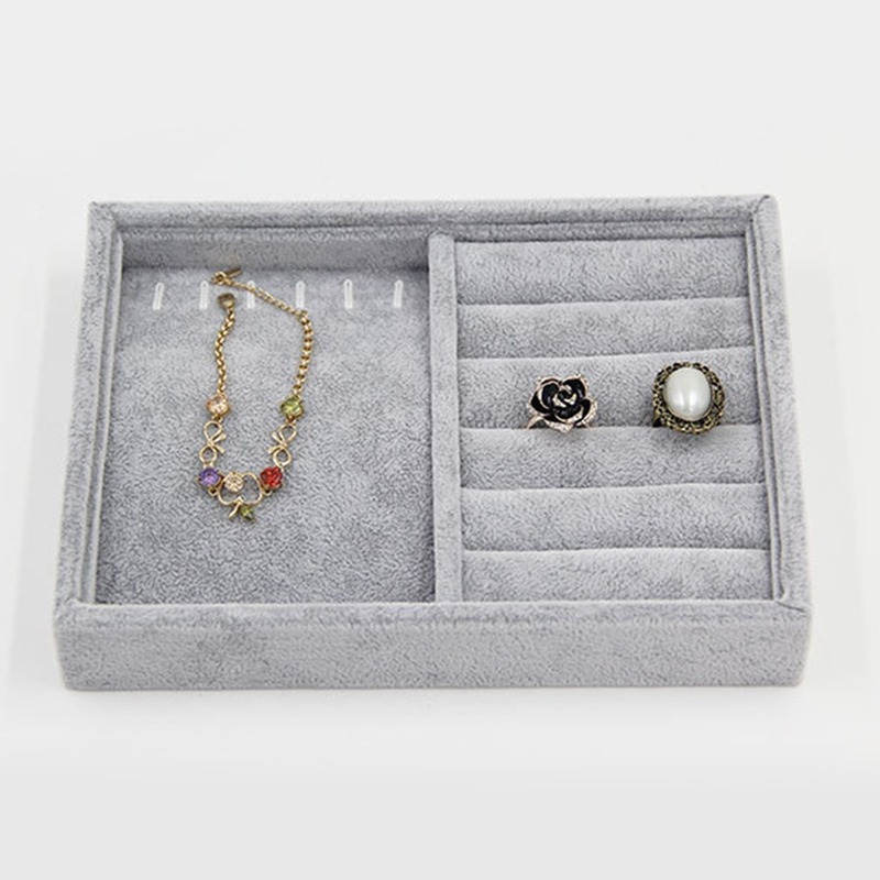 Gray velvet jewelry tray with grid compartments for stackable storage of watch accessories.