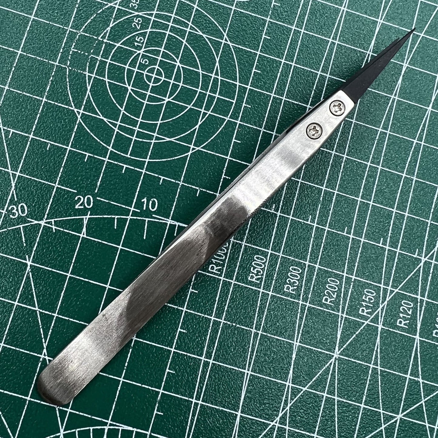 Stainless steel tweezers with carbon fiber tip, ideal for precise watch repair.