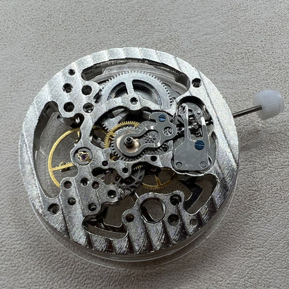 Hollow silver manual winding watch movement, highlighting precise mechanical craftsmanship.