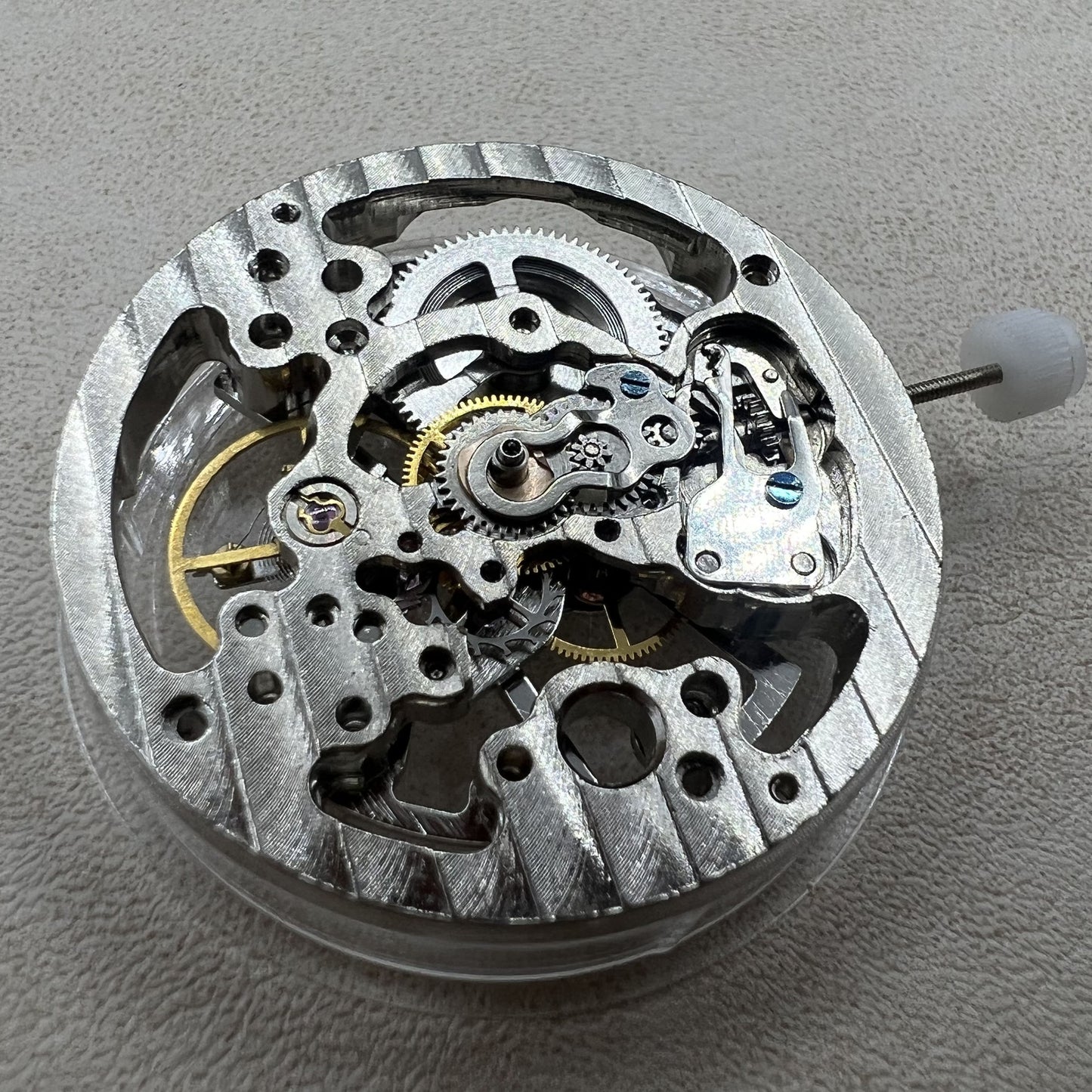 Hollow silver manual winding watch movement displaying intricate gears and craftsmanship.