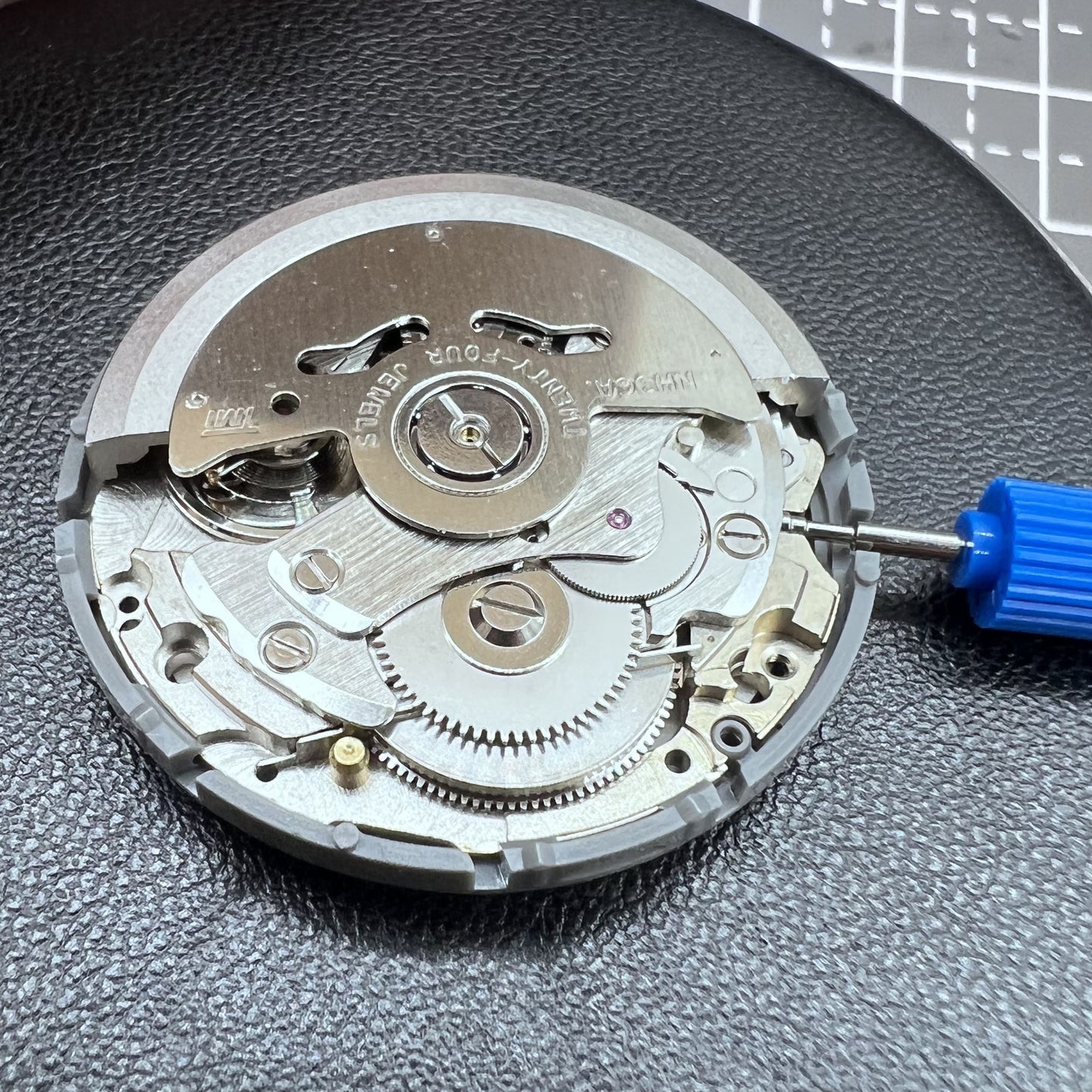 Seiko NH36A automatic watch movement with black finish and green luminescent markers, crown at 3:80 position.