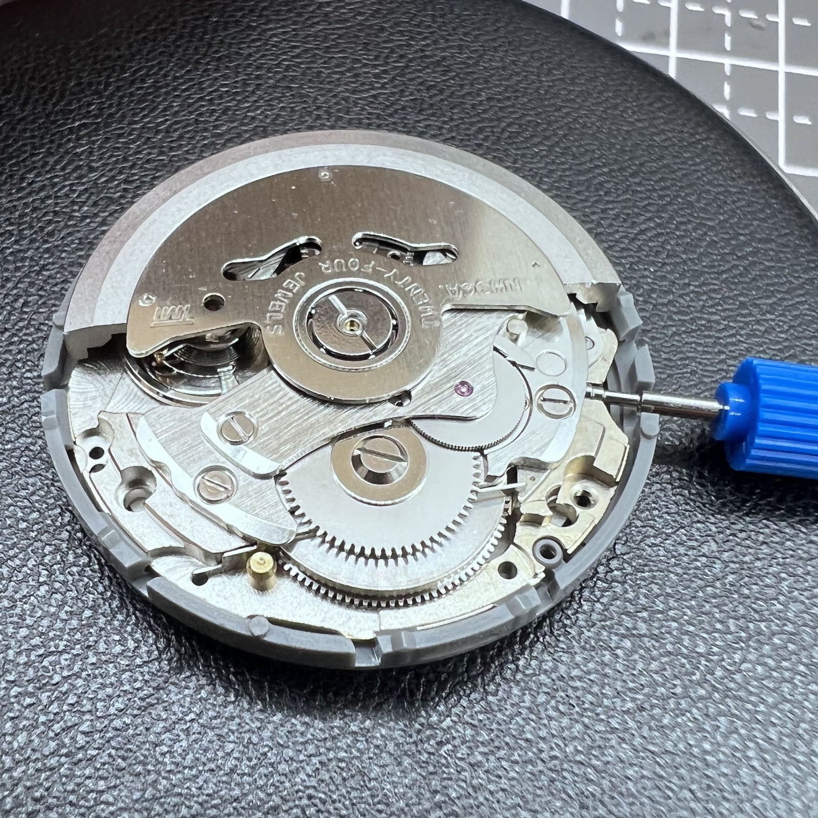 Seiko NH36A automatic watch movement with black finish and green luminescent markers, crown at 3:80 position.
