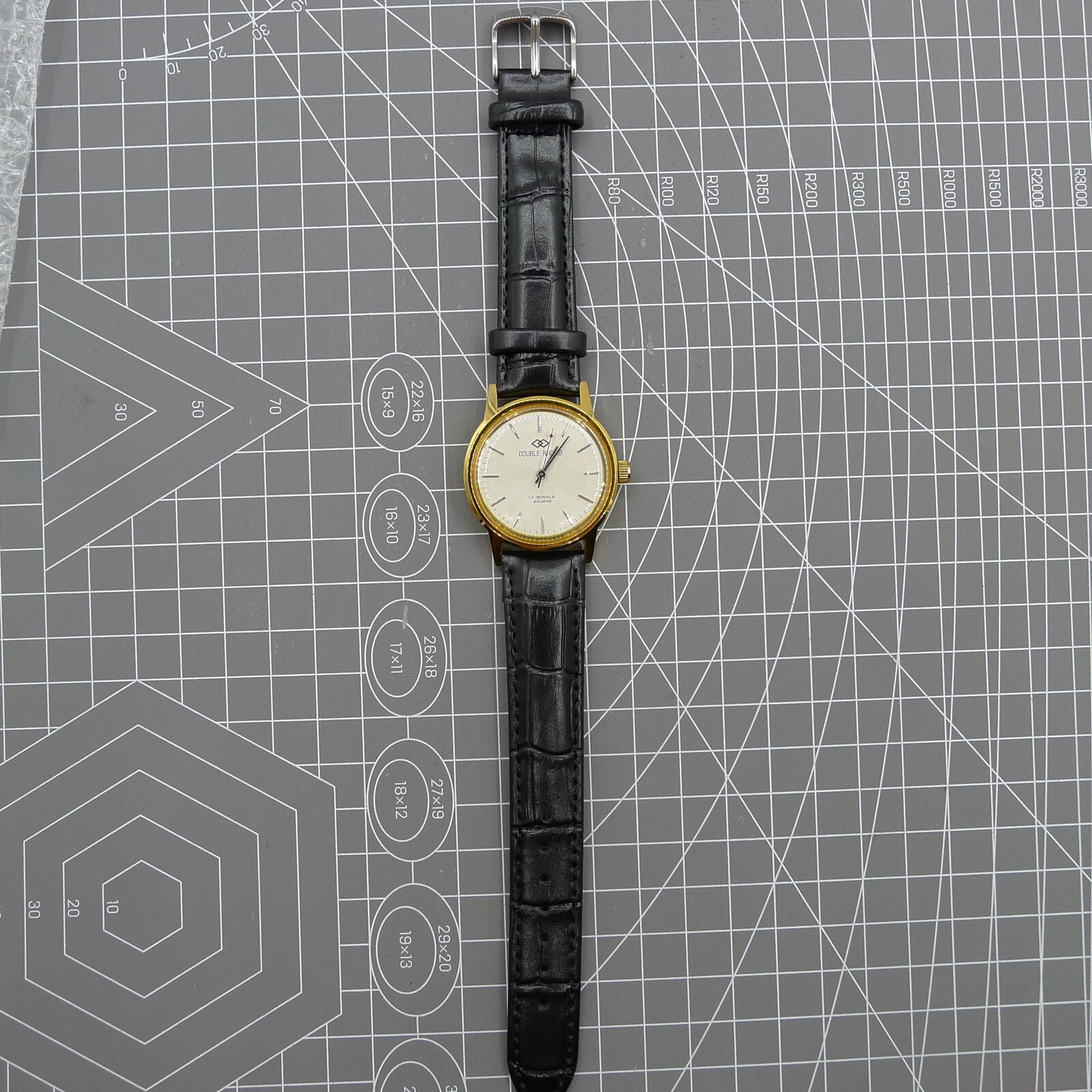 Beijing Double Rhomb watch with golden case, silver nail markers, and manual mechanical movement for classic style.