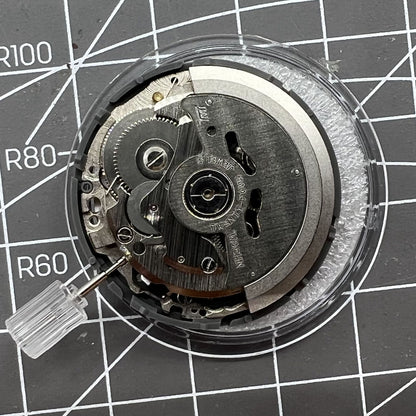 Miyota NH36A automatic watch movement with black finish, blue lume, and crown at 3.8 position for accuracy.