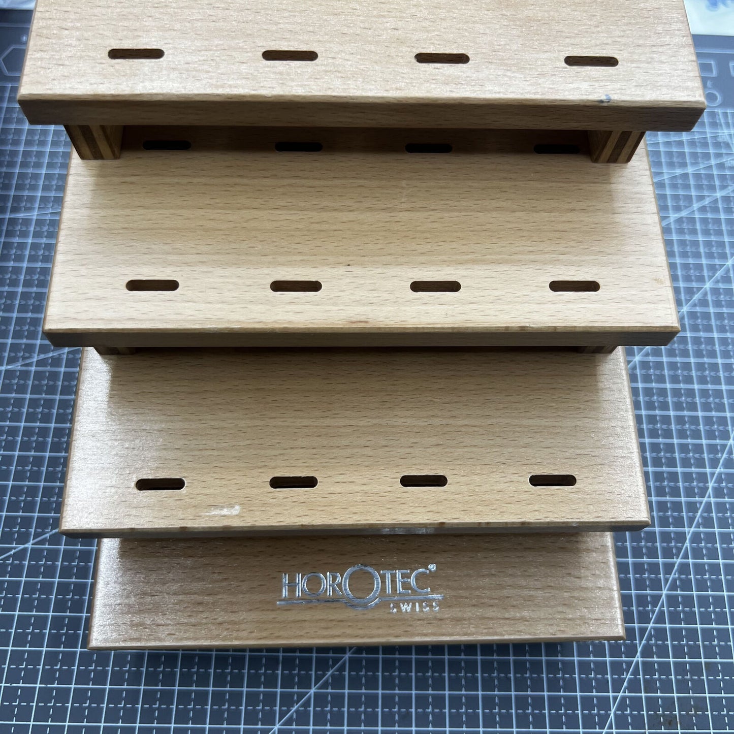 Swiss Horotec wooden storage rack holding 12 tweezers, organized watch accessory for precision tools.