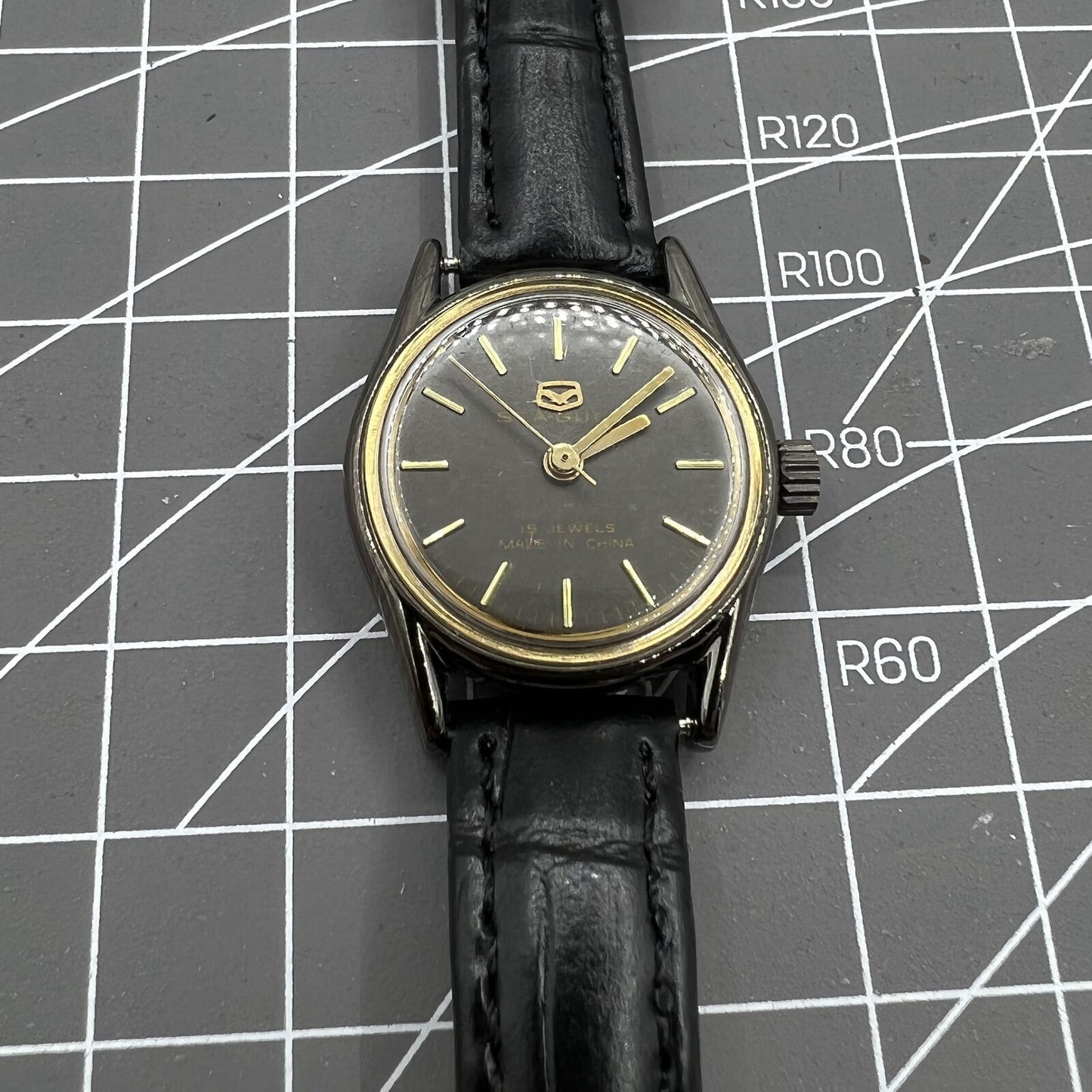 Seagull ladies watch with black case, golden nail markers, manual mechanical movement, and shock resistance.