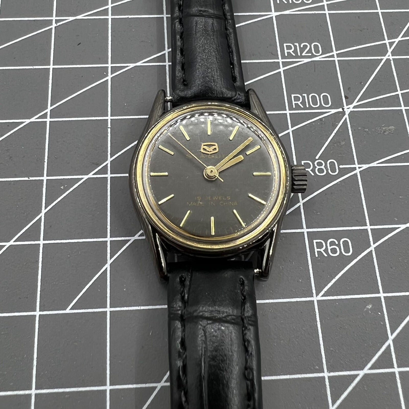 Seagull ladies watch with black case, golden nail markers, manual mechanical movement, and shock resistance.