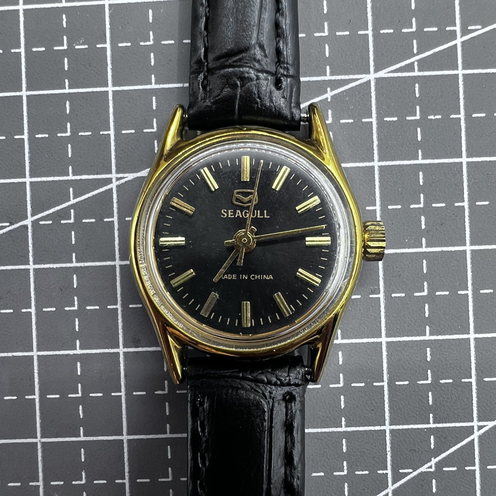 Black round case ladies watch with golden nails, Tianjin Seagull manual mechanical movement, elegant design.