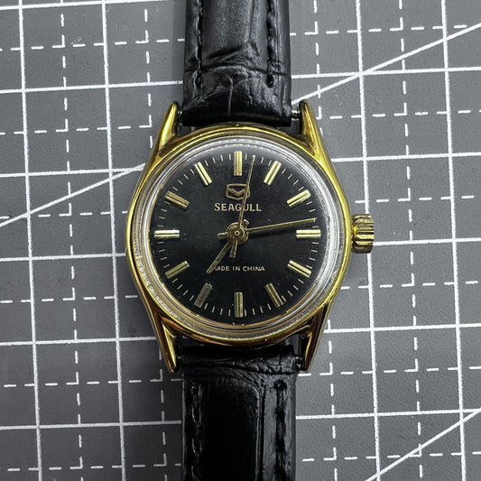 Black round case ladies watch with golden nails, Tianjin Seagull manual mechanical movement, elegant design.