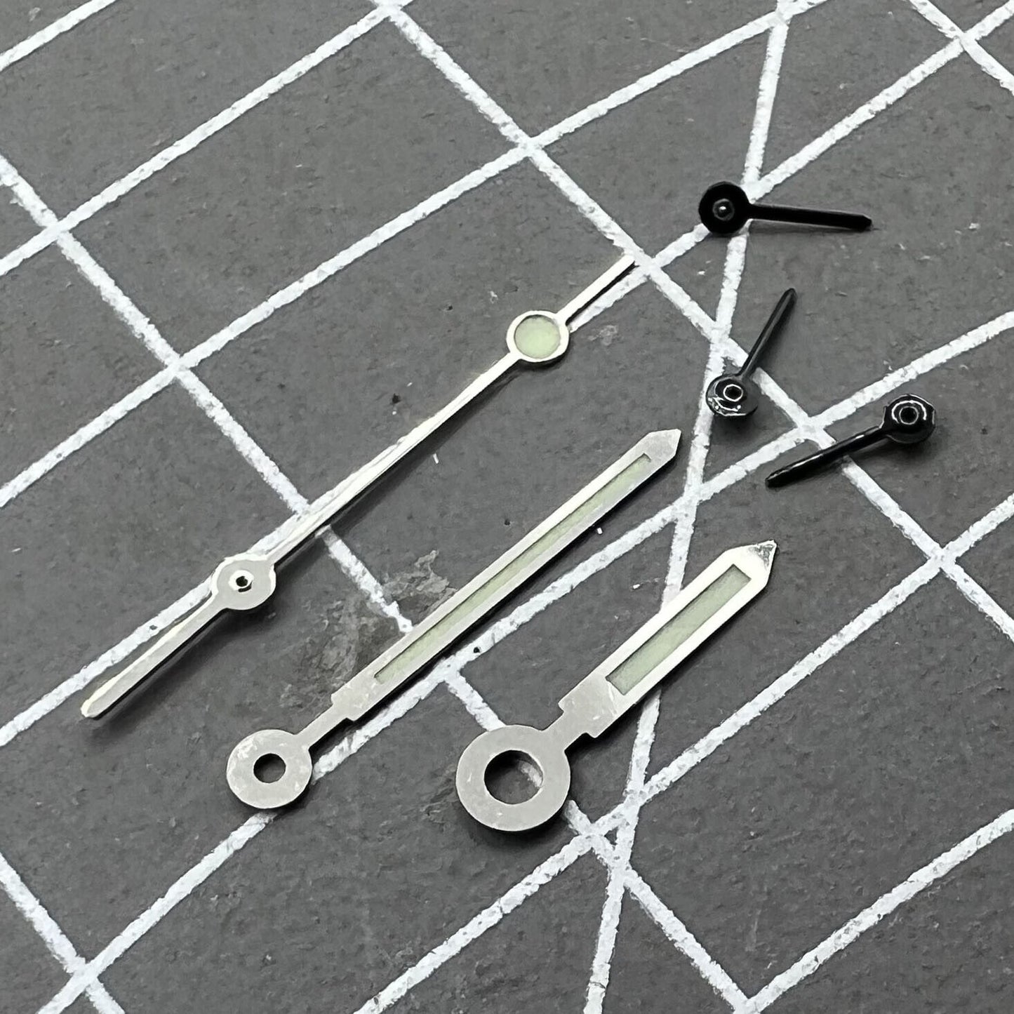 Silver-trimmed green luminous watch hands for Miyota OS10 movement, enhancing readability and style.