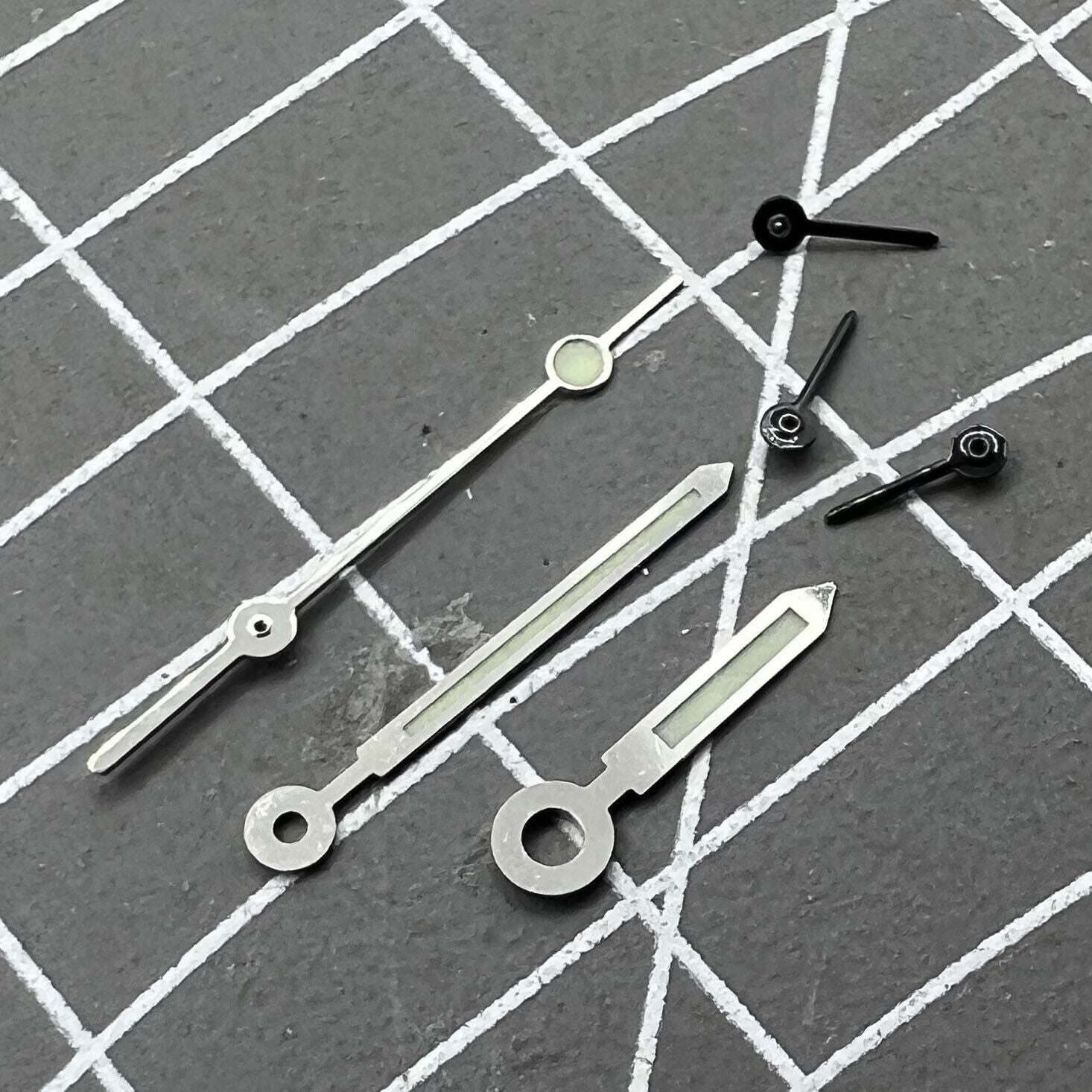 Silver-trimmed green luminous watch hands for Miyota OS10 movement, enhancing readability and style.