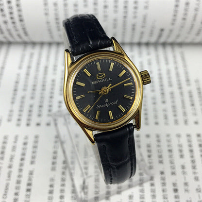 Elegant black round case ladies watch by Tianjin Seagull featuring golden nail markers and manual mechanical movement.