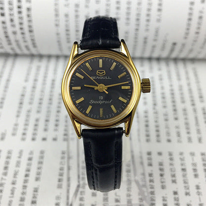 Tianjin Seagull ladies watch with black round case, golden nail markers, and manual mechanical movement for elegant style.