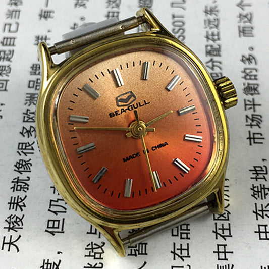 Seagull 27mm square gold case ladies watch with manual mechanical movement on orange background.