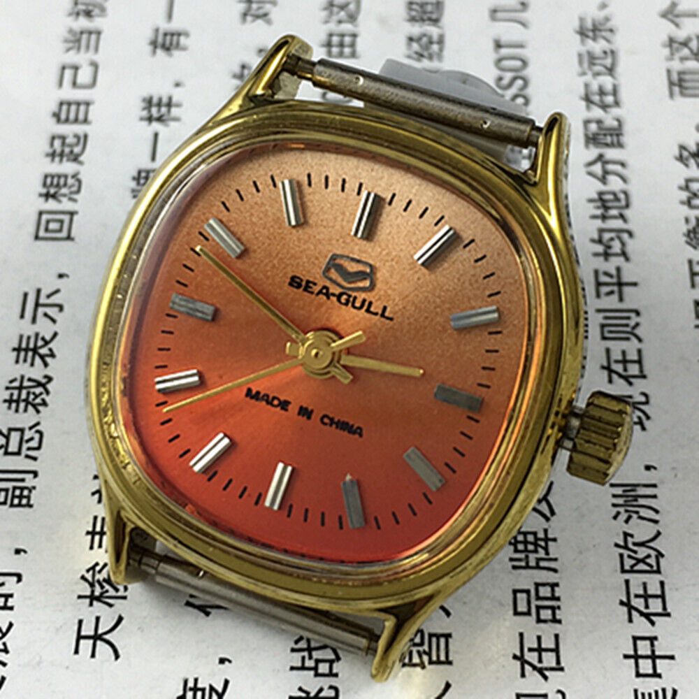 Seagull 27mm gold square ladies watch with manual movement on vibrant orange background.