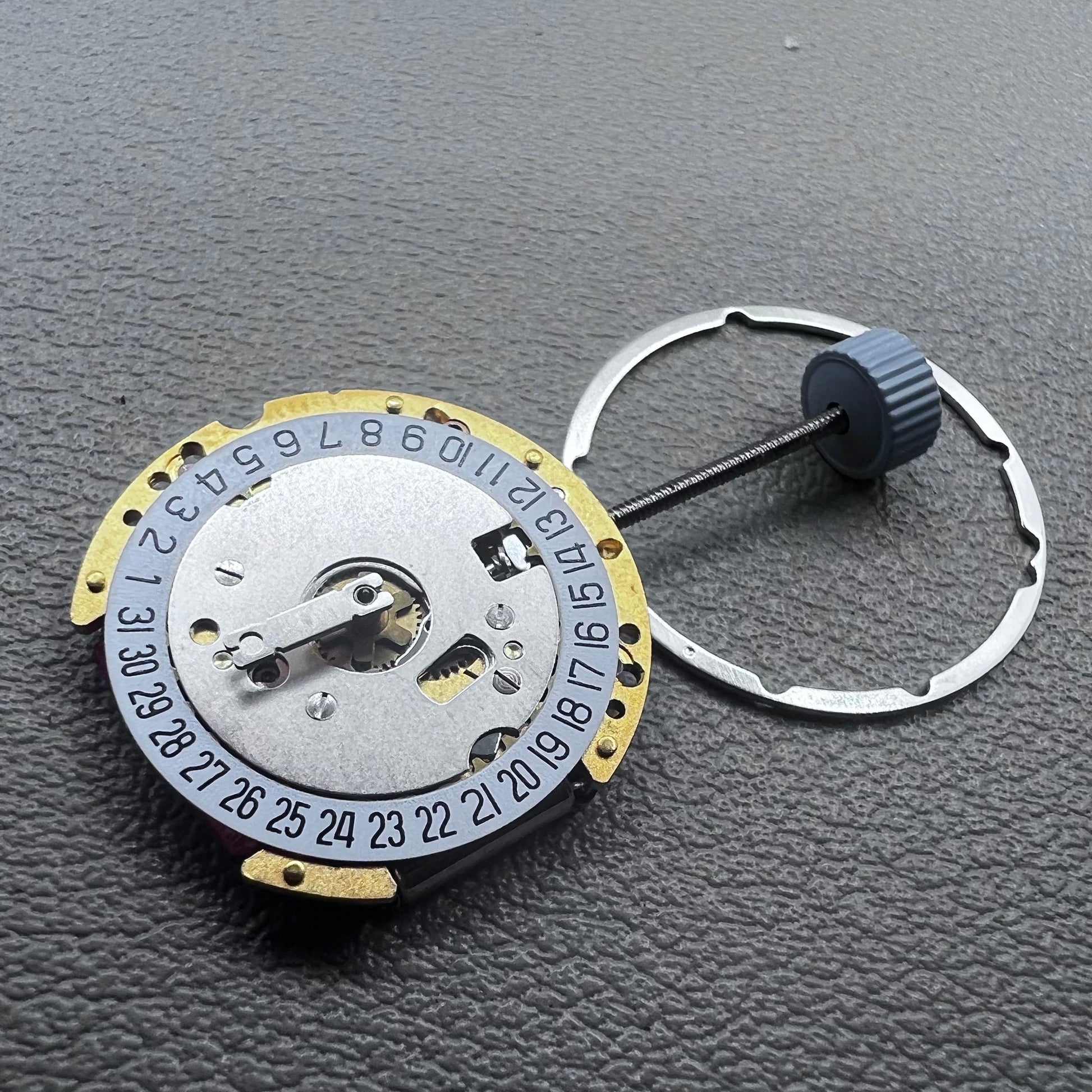 Swiss Ronda 775 quartz watch movement with golden finish, date at 6, and three hands.