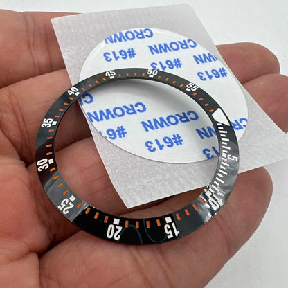 Black ceramic watch bezel insert with orange graduation, 38mm/30.5mm, durable replacement part for precise timekeeping.