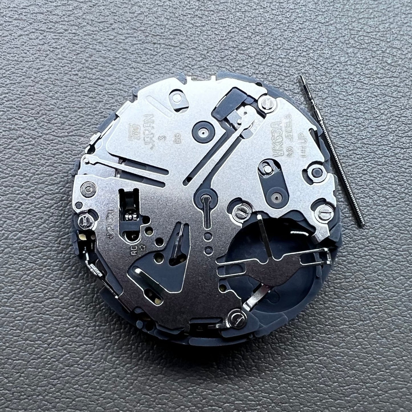 Japan Seiko VK63 quartz watch movement with black disk and white font for precise timekeeping.