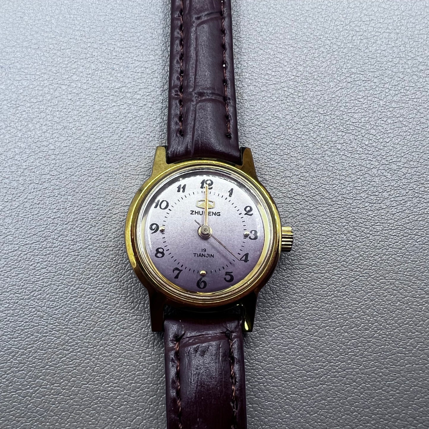 Dark Brown Strap Round Case 3 Hands Purple Background Manual Mechanical Watch