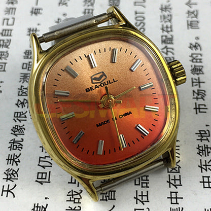 Seagull 27mm square gold watch with manual mechanical movement on vibrant orange background, elegant ladies accessory