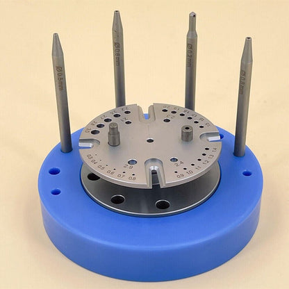 Blue rotated stand holding watch balance staff and hairspring, precision repair tool for watchmakers.