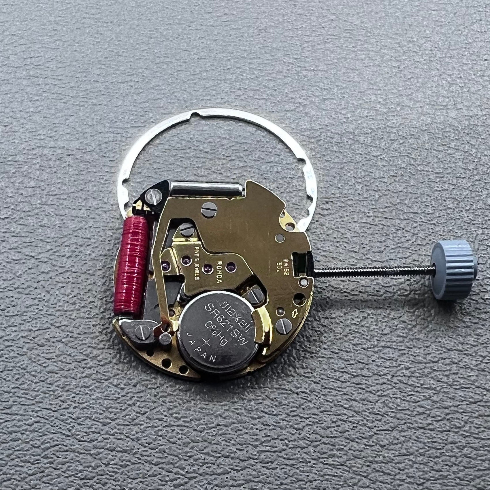 Swiss Ronda 775 quartz watch movement with golden finish, date at 6, and three hands.