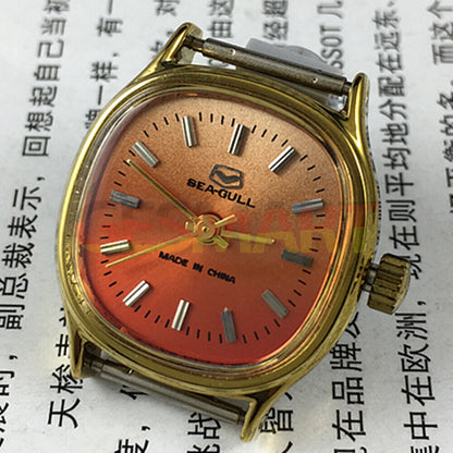 Seagull 27mm gold square ladies watch with manual mechanical movement on vibrant orange backdrop