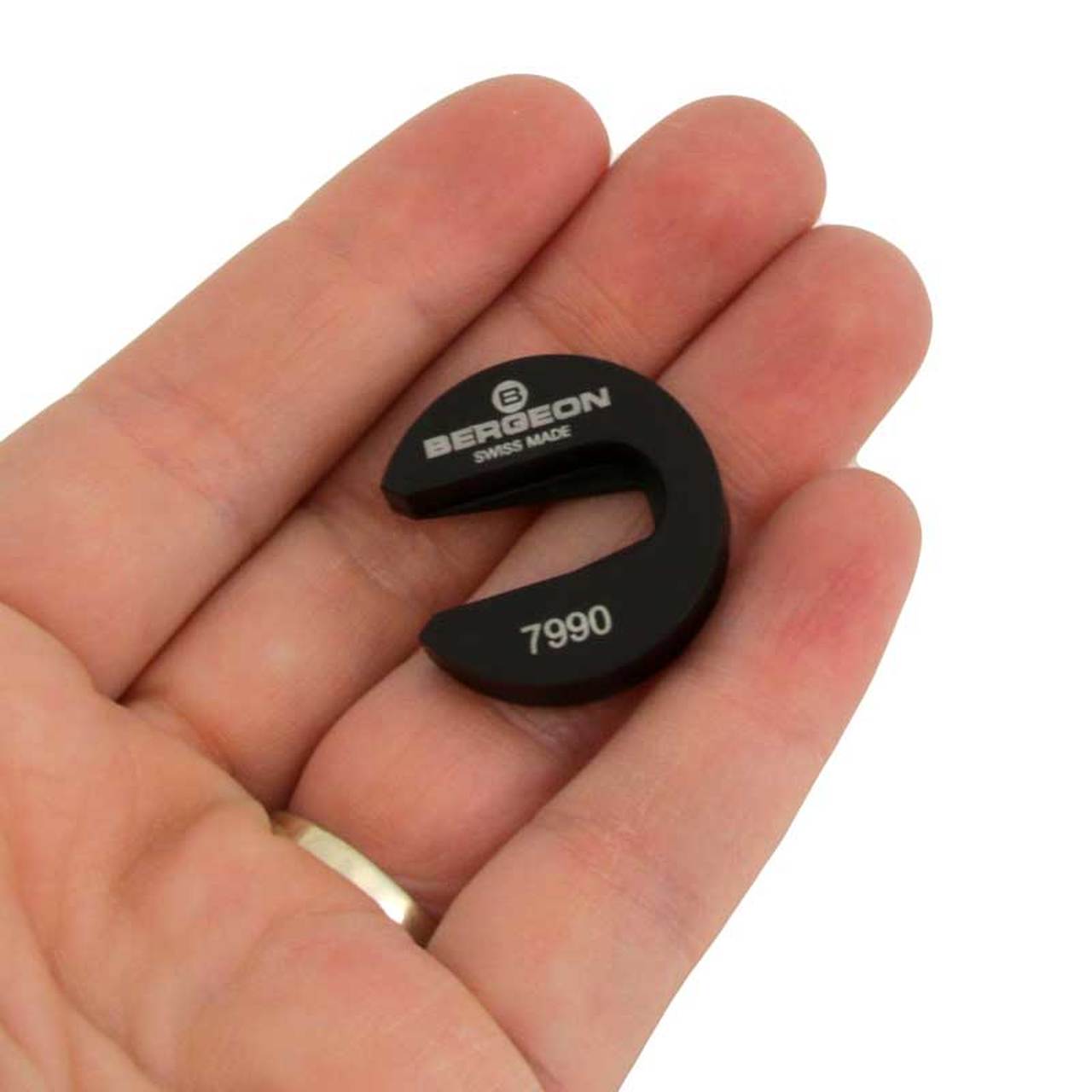 Bergeon 7990 watchmaker tool securely holding balance wheel impulse-pin for precise cleaning.