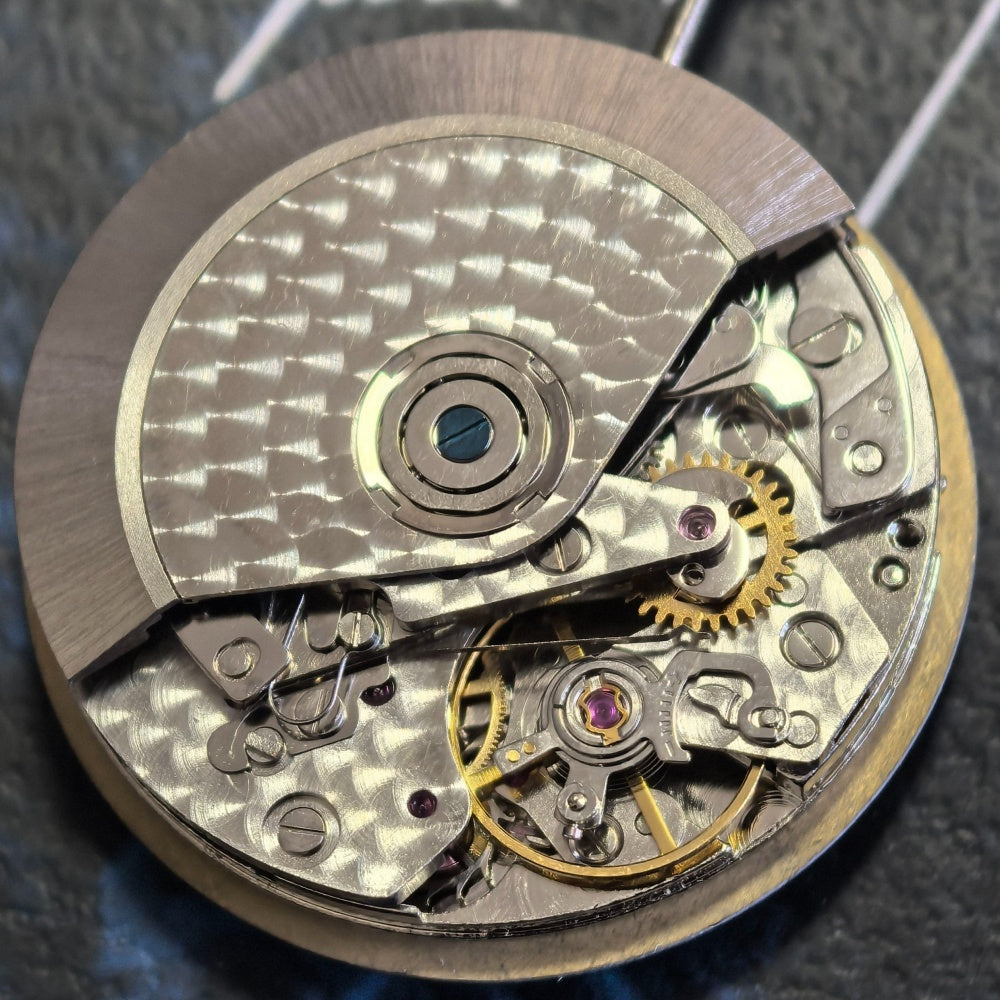 Detailed view of Chinese Dandong 7750 mechanical watch movement with small second subdials at 3, 6, and 9 o'clock positions.