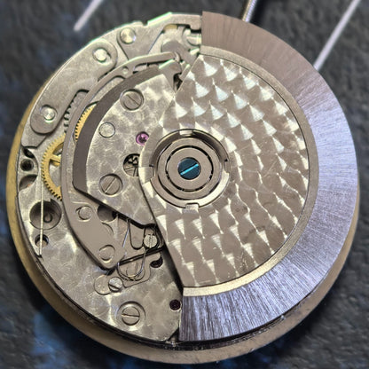 Close-up of Chinese Dandong 7750 mechanical watch movement featuring small second subdials at 3, 6, and 9 o'clock positions.
