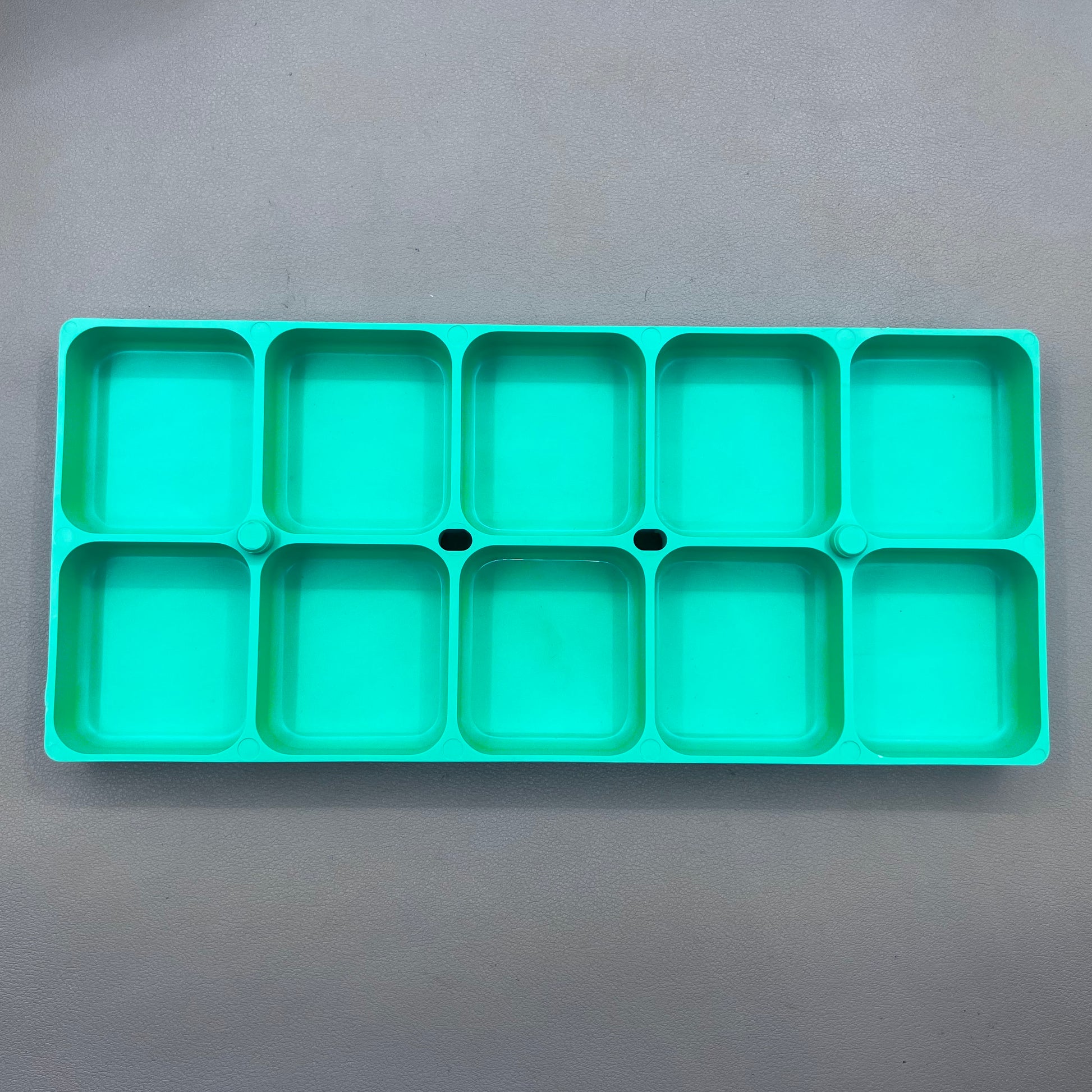 Swiss Horotec green plastic container with 10 compartments for organizing watch accessories.