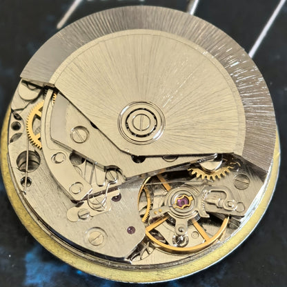 Close-up of Chinese Dandong 7750 mechanical watch movement with small second hand at 9 o'clock, 21600 bpm frequency.