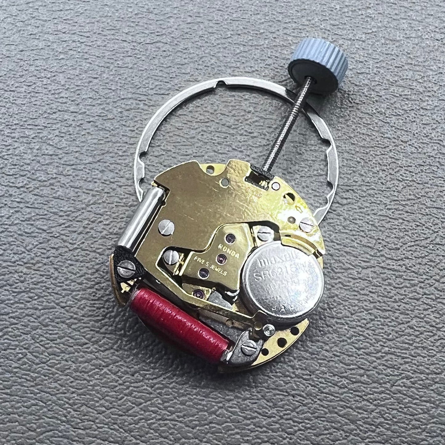 Swiss Ronda 775 quartz watch movement with golden finish, date at 6, and three hands.