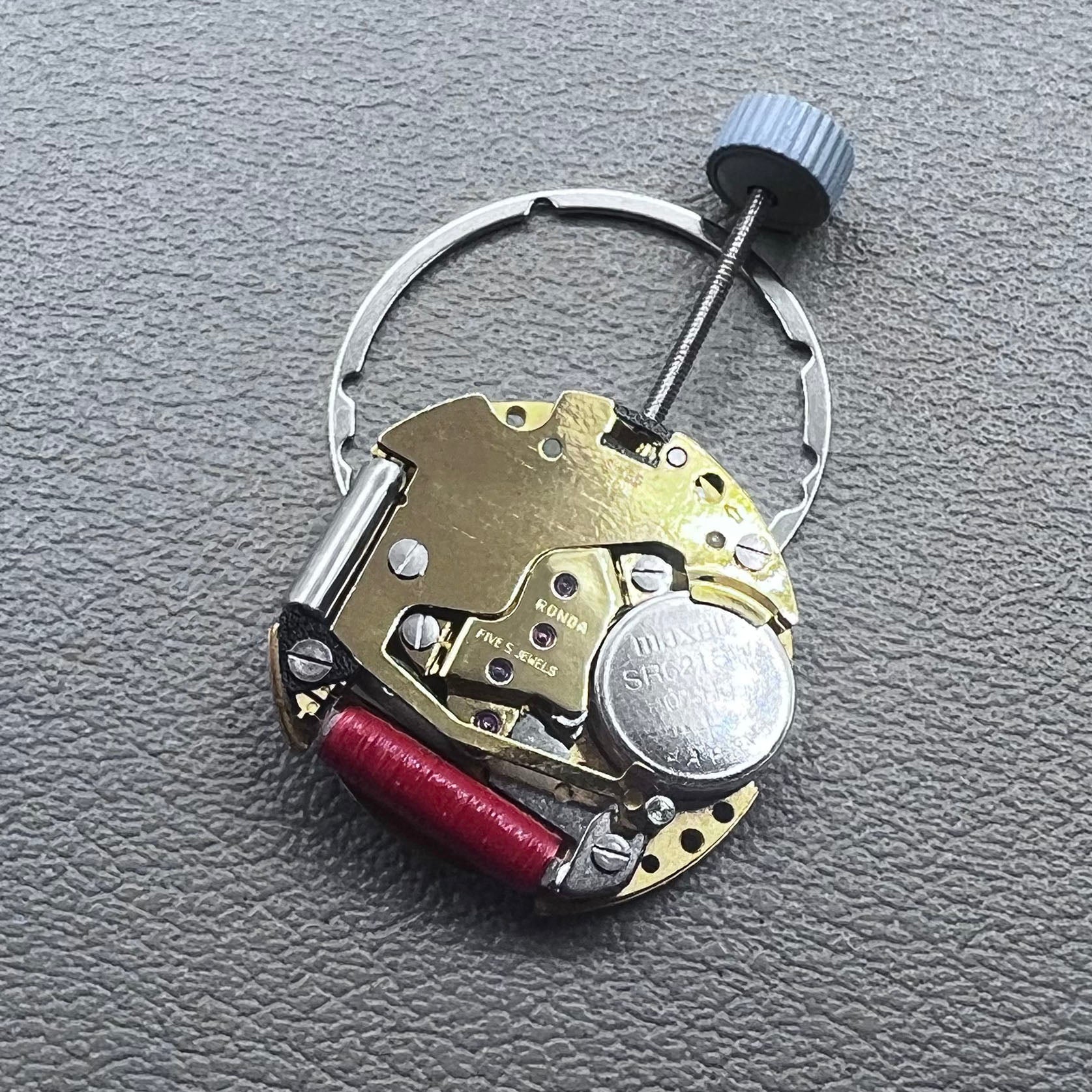 Swiss Ronda 775 quartz watch movement with golden finish, date at 6, and three hands.