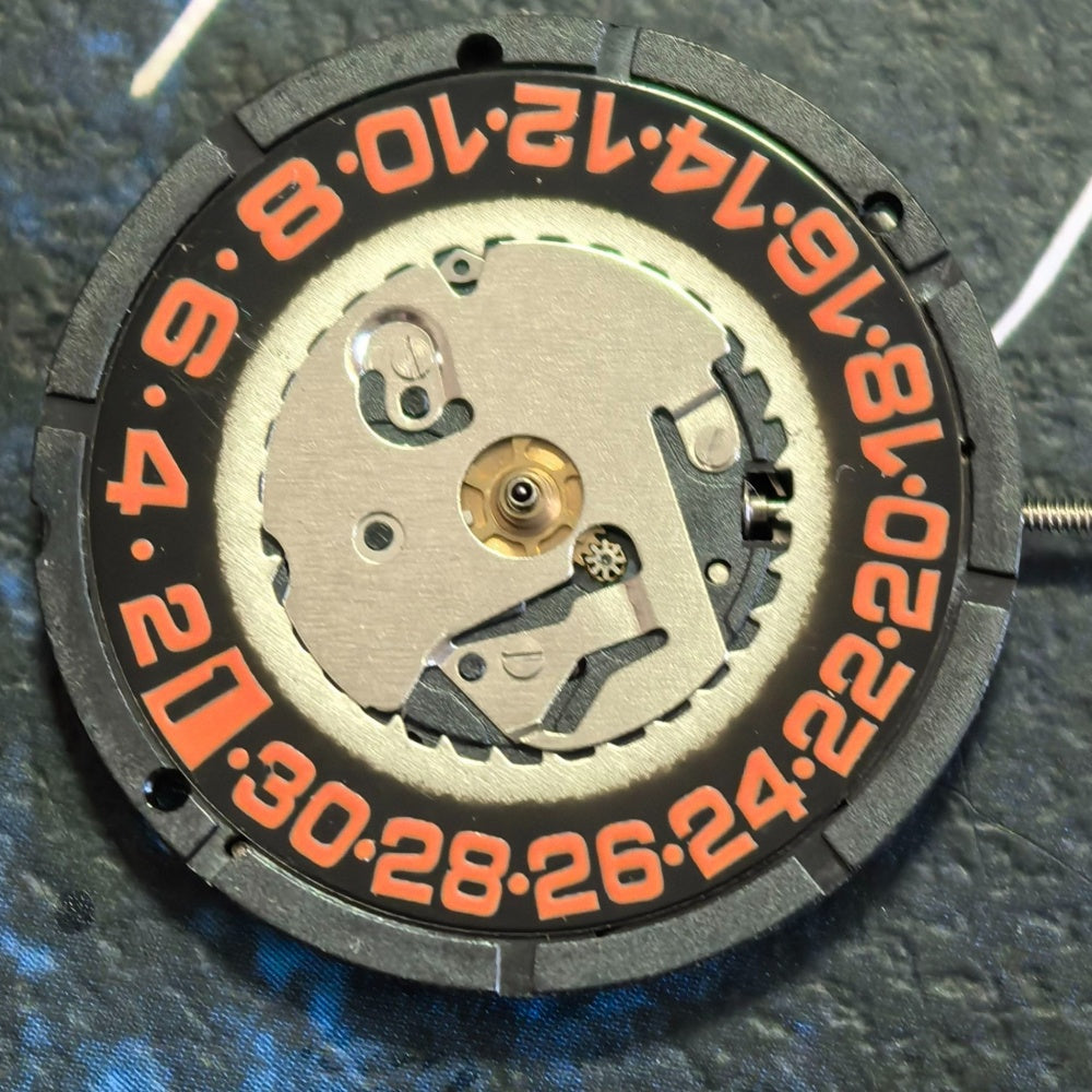 Swiss ISA 2320 quartz watch movement with black dial, orange numerals, date display at 6 o'clock.