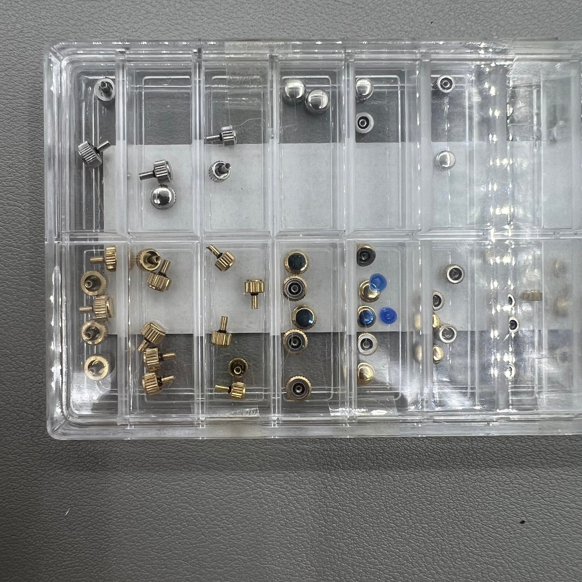 Set of 63 stainless steel watch crowns in gold and silver with 0.9mm diameter for repairs and customization.
