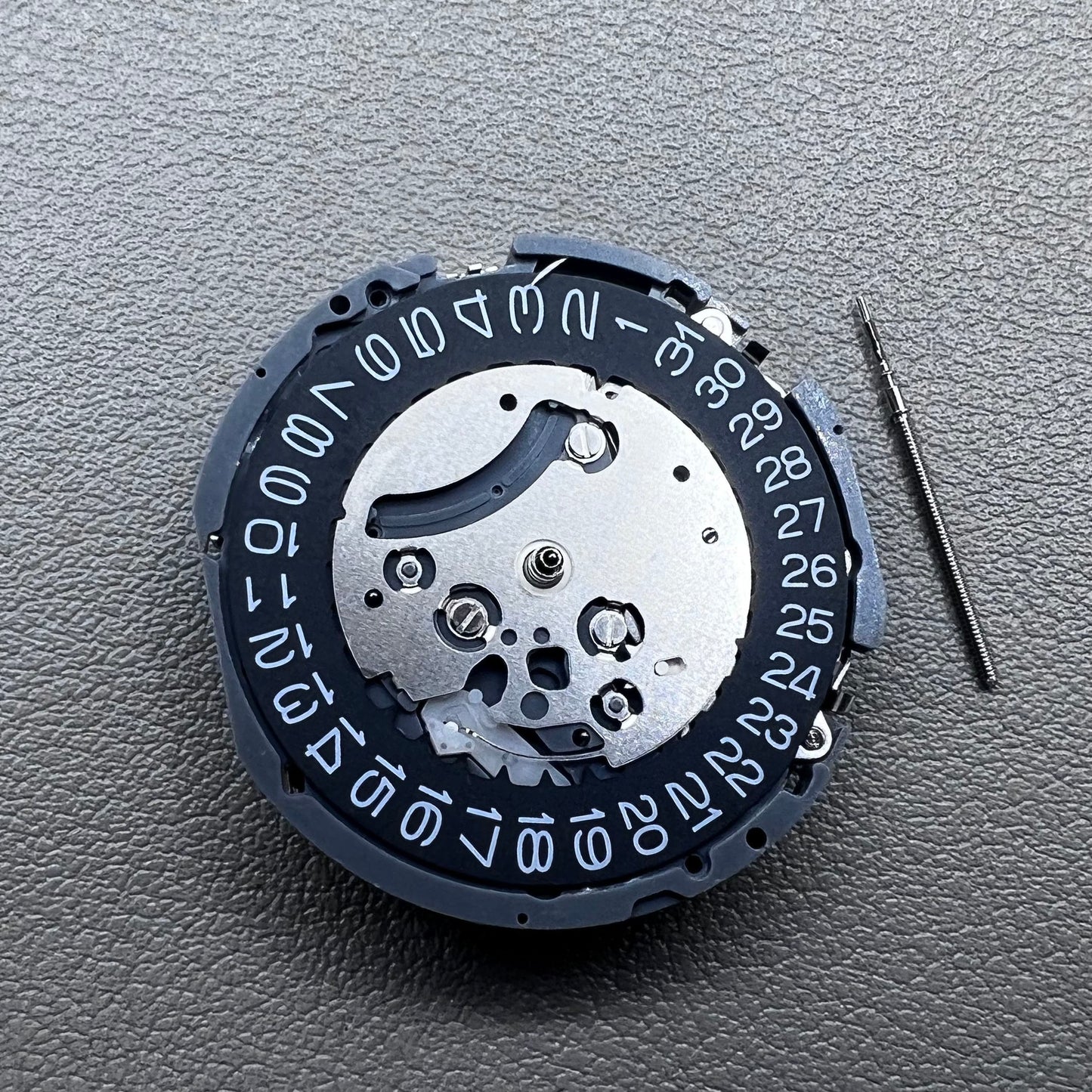 Japan Seiko VK63 quartz watch movement with black disk and white font for precise timekeeping.