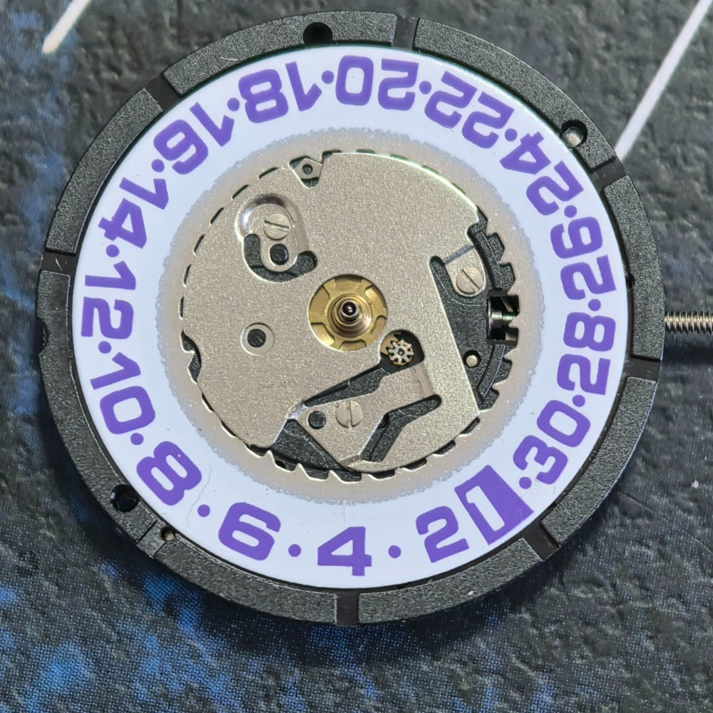 Swiss ISA 2320 quartz watch part with white disk and purple font for precise timekeeping and styling.