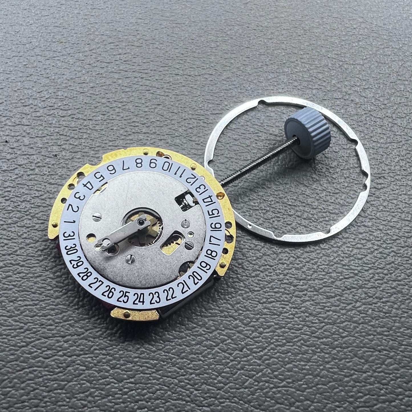 Swiss Ronda 775 quartz watch movement with golden finish, date at 6, and three hands.