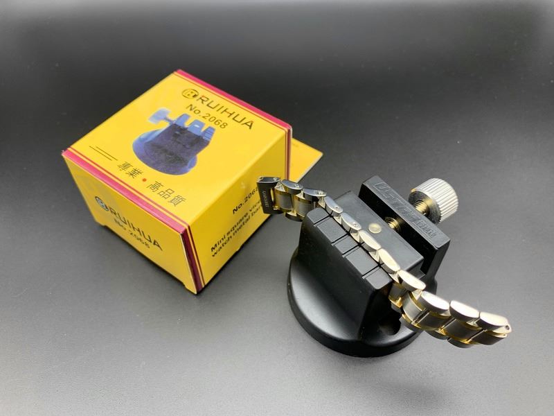 Watch band link remover tool with hammer and pins for precise bracelet repair.